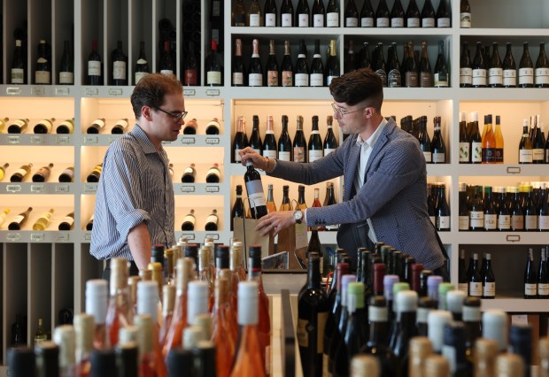 George Day-Toles, right, beverage and education manager at Verve Wine on Lincoln Avenue, bags bottles of wine for Liam Marchant, a DePaul University music student, on May 18, 2024, in Chicago. (John J. Kim/Chicago Tribune)