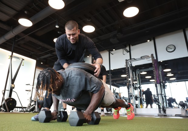 Athletes They Fear founder Kofi Hughes places two 45-pound weights on the back of Green Bay Packers wide receiver Jayden Reed as he does pushups on April 10, 2024, in Chicago. Reed began training with Hughes in high school, and their friendship continues. (John J. Kim/Chicago Tribune)