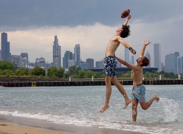 Gabriel Kenah, left, and Jake Pietryla play football in Lake Michigan on May 20, 2024, at 31st Street Beach. Chicago beaches officially open Friday for the summer. (Brian Cassella/Chicago Tribune)