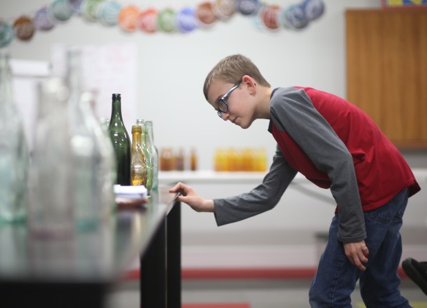 Bronson Welch, 12, chooses a bottle during an auction held at a monthly meeting of the 1st Chicago Bottle Club at Hinsdale Covenant Church on April 19, 2024. The club is an antique bottle collecting club that's been around since the 1970s. (Trent Sprague/for the Chicago Tribune)
