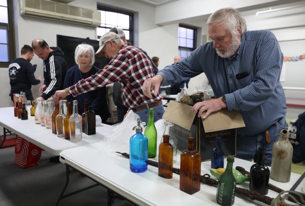 Tom Majewski, of Naperville, right, setups up his bottle display during a monthly meeting of the 1st Chicago Bottle Club at Hinsdale Covenant Church in Hinsdale on April 19, 2024. (Trent Sprague/for the Chicago Tribune)