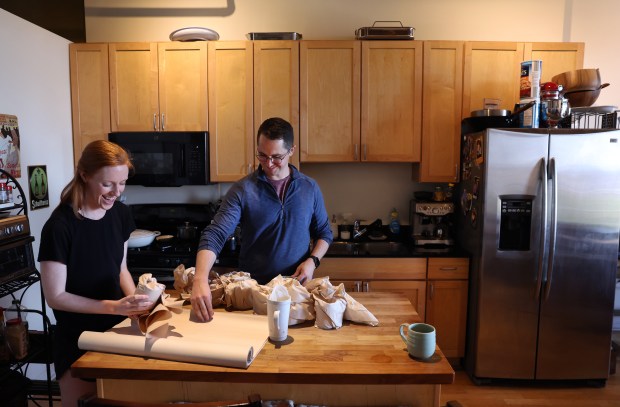 Busy and Charlie Deeter use paper to protect their glassware as the couple packs up their belongings for their move to a rental apartment in Ravenswood on May 4, 2024. (Chris Sweda/Chicago Tribune)