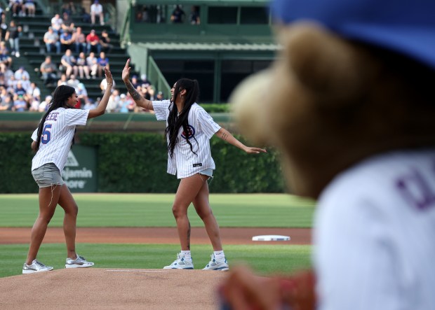 New Chicago Sky players Angel Reese (left) and Kamilla Cardoso high five after throwing out a ceremonial first pitches before a game between the Chicago Cubs and the Atlanta Braves at Wrigley Field in Chicago on May 21, 2024. (Chris Sweda/Chicago Tribune)