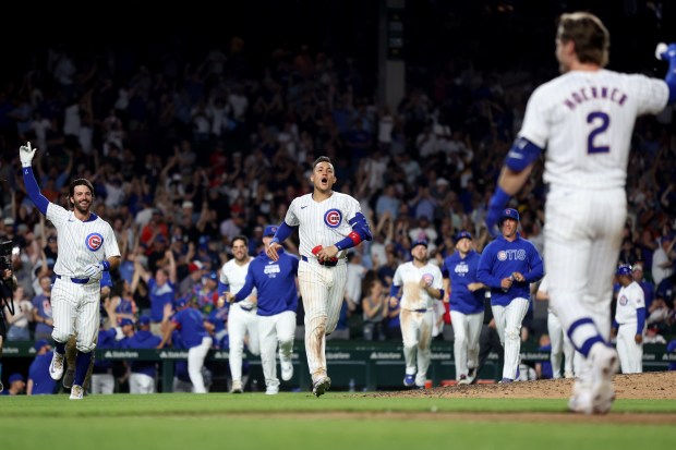 Chicago Cubs players, including Dansby Swanson (left) and Miguel Amaya (center), come out to congratulate second baseman Nico Hoerner (2) after he drove in the game-winning walk off infield single in the 10th inning of a game against the Atlanta Braves at Wrigley Field in Chicago on May 21, 2024. (Chris Sweda/Chicago Tribune)