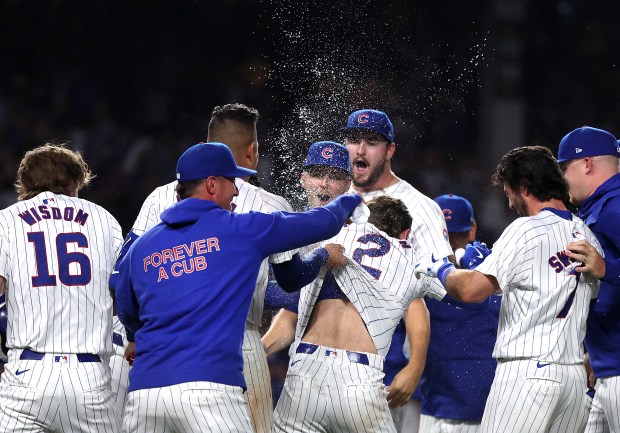 Chicago Cubs players come out to congratulate second baseman Nico Hoerner (2) after he drove in the game-winning walk off infield single in the 10th inning of a game against the Atlanta Braves at Wrigley Field in Chicago on May 21, 2024. (Chris Sweda/Chicago Tribune)