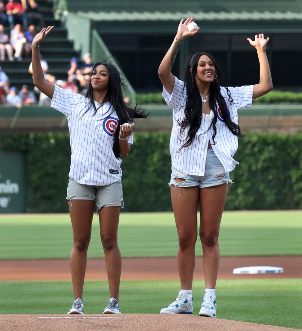 New Chicago Sky players Angel Reese (left) and Kamilla Cardoso (right) wave to the crowd before throwing out a ceremonial first pitch before a game between the Chicago Cubs and the Atlanta Braves at Wrigley Field in Chicago on May 21, 2024. (Chris Sweda/Chicago Tribune)