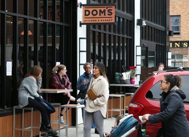 People linger in the parking lot of Dom's Kitchen and Market on Halsted Street at Diversey Parkway in Chicago after the store was abruptly shut down April, 23, 2024. (Terrence Antonio James/Chicago Tribune)