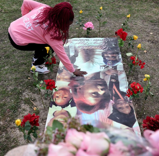 Misty Tiggs clears off a banner featuring various images of her daughter at the gravesite of Rickisha King-Tiggs at Forest Home Cemetery on March 29, 2024. Misty celebrated Rickisha's birthday, who would have turned 27, with a small group of friends and family. (Chris Sweda/Chicago Tribune)