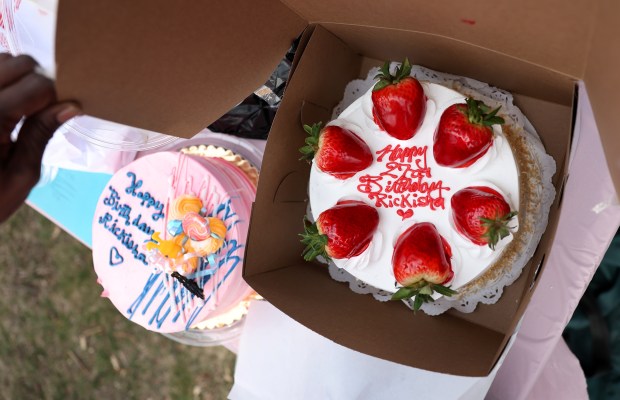 Misty Tiggs opens a cake box while celebrating the birthday of her late daughter, Rickisha King-Tiggs at Forest Home Cemetery on March 29, 2024. (Chris Sweda/Chicago Tribune)