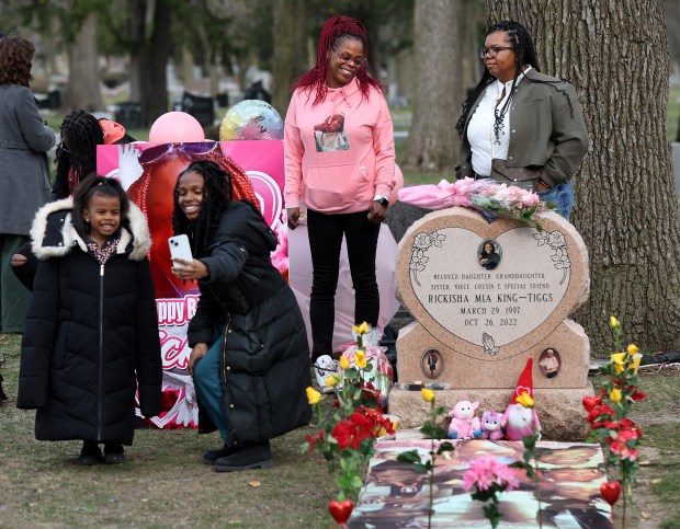 Misty Tiggs, center, chats with Juatise Gathings, right, at the gravesite of Tiggs' daughter Rickisha King-Tiggs as friends and family celebrate the birthday of Rickisha at Forest Home Cemetery on March 29, 2024. At left, Rickisha's friend Rose Lewis takes a photograph with her daughter Zuri, 6. (Chris Sweda/Chicago Tribune)