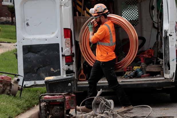 A worker carries new copper pipe during a lead service line replacement project for a home in the 10100 block of south Green Street in Chicago, May 2, 2024. (Antonio Perez/Chicago Tribune)