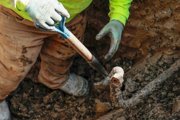 A worker removes a lead service line as a crew replaces it with a copper pipe for a homeowner in the 10100 block of south Green Street in Chicago, May 2, 2024. (Antonio Perez/Chicago Tribune)