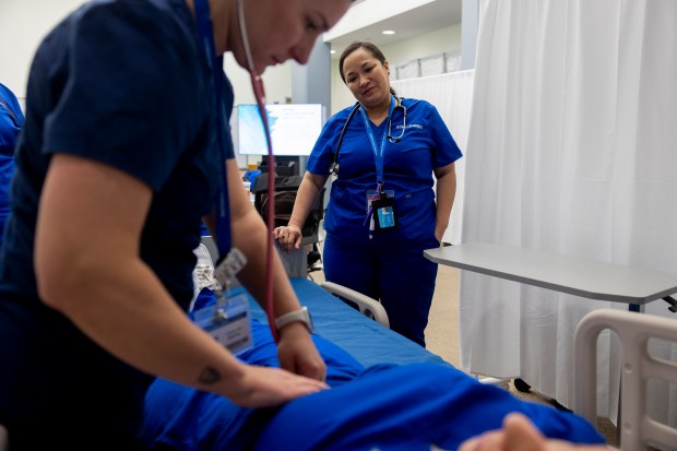 Lara Romero returned to get her bachelor's degree in nursing 18 years after having her first child, watches as Audrey Peri, a clinical instructor, performs an abdominal assessment exercise during a lab class, May 10, 2024, at National Louis University in Chicago. (Vincent Alban/Chicago Tribune)