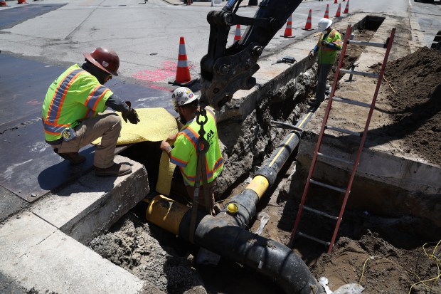 Lino Banuelos, left, Jake Schraeger, center, and Juan De Luna, from Miller Pipeline, put the finishing touches on a section of a Peoples Gas pipeline replacement project at Wrightwood and Sheffield avenues in Chicago on May 29, 2024. The project started at Seminary Avenue and will continue east toward Clark Street. (Terrence Antonio James/Chicago Tribune)