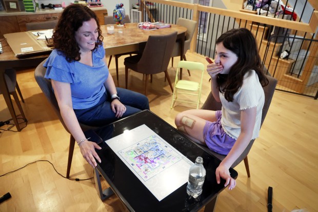 Marci Sieracki, left, plays a game with her daughter Natalie Sieracki, 9, at thier home in Chicago on May 7, 2024. Natalie was severely bitten by an unleashed dog at Horner Park in Chicago days earlier. (Terrence Antonio James/Chicago Tribune)