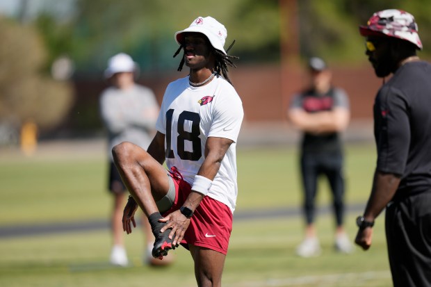 Arizona Cardinals rookie wide receiver Marvin Harrison Jr., left, warms up during an NFL rookie minicamp football practice as Cardinals assistant strength and conditioning coach Everrett Gathron, right, looks on Friday, May 10, 2024, in Tempe, Ariz. (AP Photo/Ross D. Franklin)