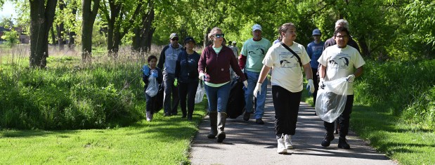 From left, Hazel Kuhse, 10, a fourth-grader from Highland Park, Hazel's parents Todd Kuhse and Sandy Oh, and also Liz Ricketts, natural areas manager for the Park District of Highland Park , walk with volunteers before they disperse in smaller groups at the 32nd annual Chicago River Day cleanup location in Highland Park at The Preserve at Highland Park on May 11, 2024.