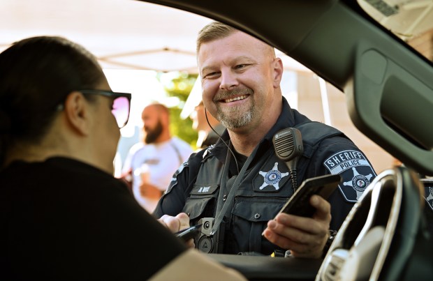 Mark Vice, deputy sheriff with the Lake County Sheriff's Police and a member of a Special Olympics law enforcement board, collects a donation from a motorist at the drive-thru at 280 S. US Highway 12 in Volo at Cop on a Rooftop on May 17, 2024 at Dunkin' in Volo. (Karie Angell Luc/Lake County News-Sun)