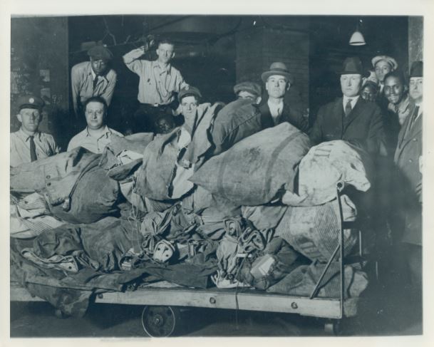 Postal workers pose with mail sacks recovered from the Rondout train robbery. The sacks were unloaded in the "hole" at the Chicago Post Office, according to the historical archive. The hole was reserved space in the base of the old main post office for future Congress Parkway extension, the caption said. (Credit: Libertyville Historical Society, Courtesy of Jim Moran)