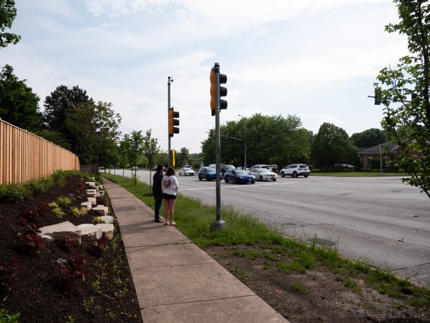 Ryan Daly, right, and his daughter Kendall look out at the busy T-intersection at Washington Street and Naper Boulevard in south Naperville, which runs right up against their home. (Tess Kenny/Naperville Sun)