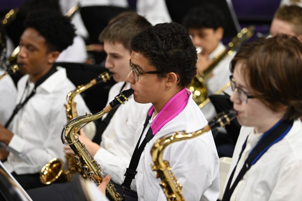 Center, with magenta strap holding a tenor saxophone is Logan Eaton-Strong, an Evanston Township High School freshman, at Northwestern University's Welsh-Ryan Arena at McGaw Memorial Hall in Evanston on May 19, 2024. (Karie Angell Luc/Pioneer Press)