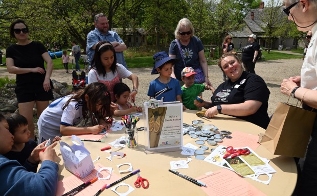 Right, seated, Diane J. Michalski, recreation program supervisor for the Glenview Park District, helps people make 2024 cicada buttons at the Cicada Celebration and Exhibit Grand Opening event on May 4, 2024 at The Grove National Historic Landmark (Karie Angell Luc/Pioneer Press)