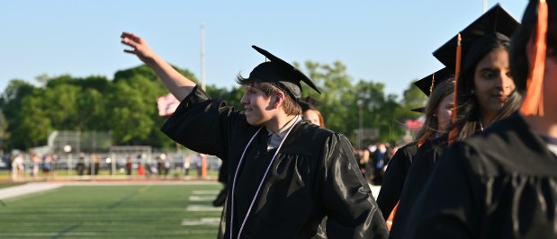 Waving to family members in the stands is Leonardo Delgado of Mount Prospect at the 55th Commencement on May 22, 2024 at John Hersey High School at Roland R. Goins Stadium. (Karie Angell Luc/Pioneer Press)