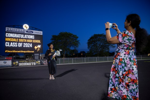 Graduate Ann Valiathara has her photo taken in front of the scoreboard by her mother Roji Valiathara after the Hinsdale South High School commencement ceremony on the football field Thursday, May 23, 2024 in Darien, Illinois. ( John Konstantaras-Pioneer-Press ) - PPN-L-Hinsdale-South-Grad-0530 00077849A