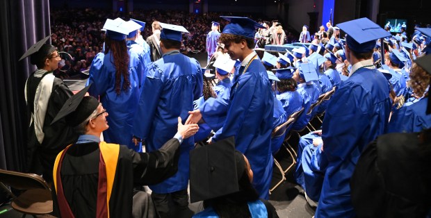 Backstage, from left, David Schultz, science teacher, shakes the hand of graduate Adam Gasior before Gasior receives a diploma at Maine East High School's graduation in Rosemont on May 19, 2024 at the Rosemont Theatre. (Karie Angell Luc/Pioneer Press)