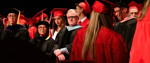 In the blue hood detail on the black gown, facing, is retiring Maine Township High School District 207 Superintendent Ken Wallace as graduates file on stage at commencement for Maine South High School in Rosemont on May 19, 2023 at the Rosemont Theatre (5400 N. River Road). (Karie Angell Luc/Pioneer Press)