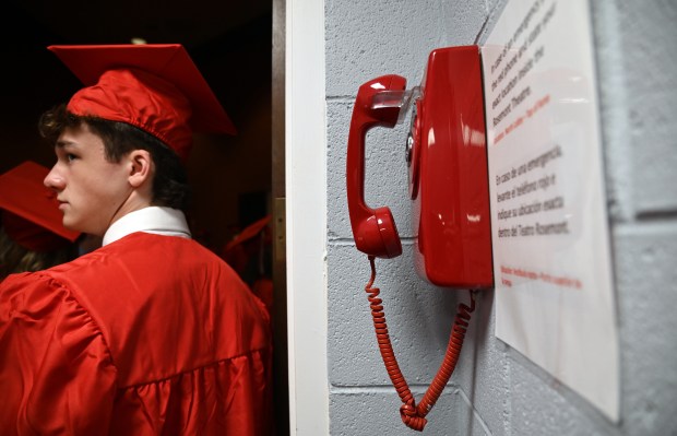 Waiting backstage to file into the auditorium for graduation is Declan O'Connell, 18, of Park Ridge at commencement for Maine South High School in Rosemont on May 19, 2023 at the Rosemont Theatre. Wall-mounted phones not something these teens are familiar with. (Karie Angell Luc/Pioneer Press)