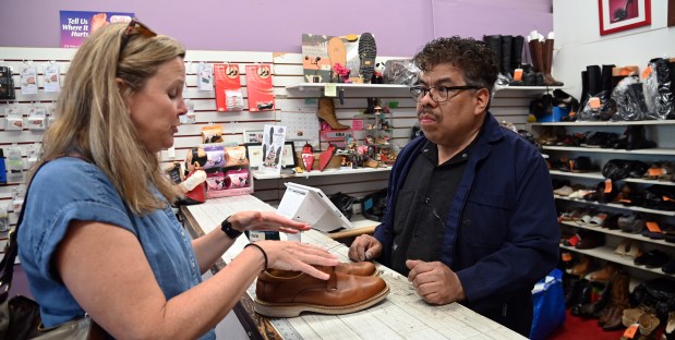 From left, Cindy Miller of Northbrook brings in a pair of shoes for new shoelaces to Oscar Ruiz of Deerfield, owner of Philip's Shoe Clinic of Northbrook, on April 30, 2024. (Karie Angell Luc/Pioneer Press).