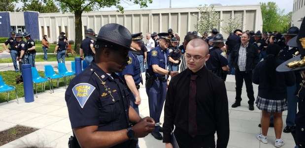 Indiana State Police First Sgt. Terrance Weems explained the significance of the department's challenge coin to Aidn Chesner, 15, of Lowell, who received the coin after performing "TAPS" at Monday's memorial service at the Lowell Post. (Carrie Napoleon/Post-Tribune)