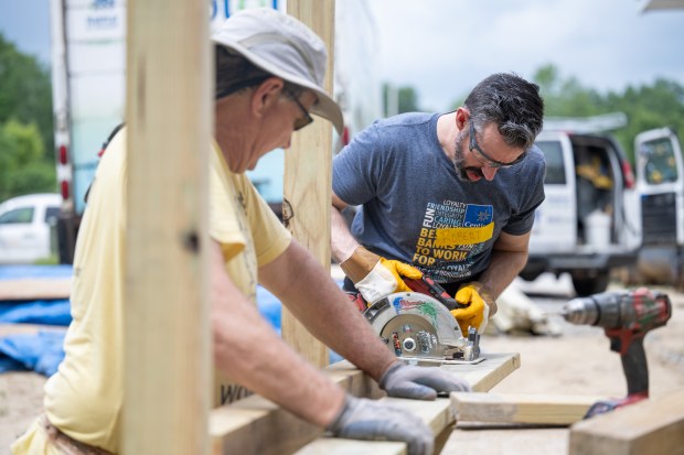New volunteer Robert Decrescentis, on right, cuts a plank for a deck with assistance from four-year volunteer Jim Horgash as people gather to participate in Habitat For Humanity Northwest Indiana's Honor Build event on Friday, May 24, 2024. (Kyle Telechan/for the Post-Tribune)