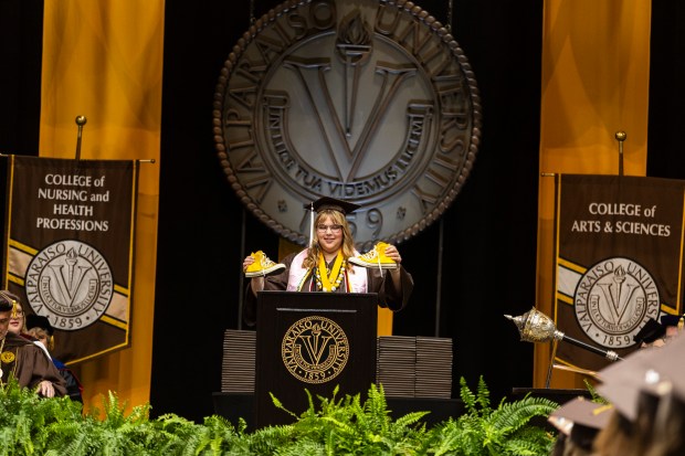 Valparaiso University class of 2024 student Jillian Elizabeth Seeger, holds up her pair of yellow-Valpo U Converse sneakers as she started speaking as part of the senior class class remarks during their commencement ceremony on Saturday, May 11, 2024, in Valparaiso. (Vincent D. Johnson/for the Post-Tribune)