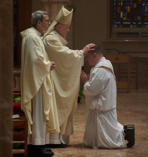 Cardinal Blase J. Cupich, archbishop of Chicago, lays hands on Deacon Timothy Berryhill, invoking the Holy Spirit, as the Very Rev. John Kartje, left, looks on during the deacon's ordination as a priest May 18 at Holy Name Cathedral in Chicago. (Chris Strong)