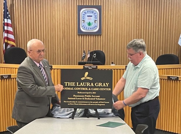 Oak Forest Mayor Hank Kuspa, left, and Terry Grey unveil a plaque April 9 after the city renamed the Oak Forest Animal Control & Care Center in honor of longtime volunteer Laura Gray, Terry Gray's wife who died less than two months earlier. (Chrissy Maher)