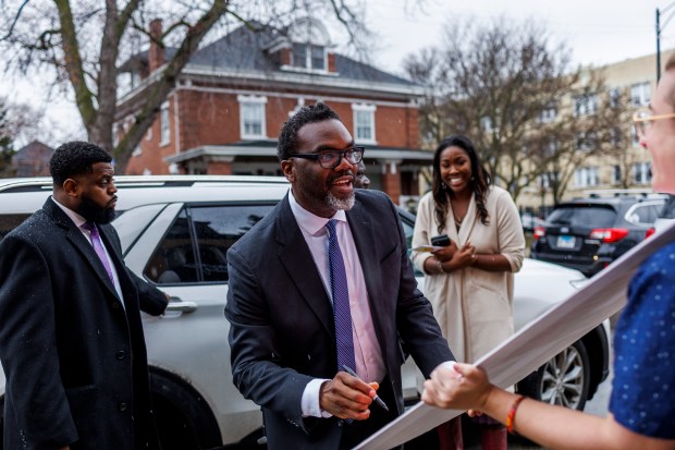 Chicago mayoral candidate Brandon Johnson signs Sam Rose's poster while attending a Bring Chicago Home public hearing at the Grace Church of Logan Square on March 12, 2023, in Chicago. (Armando L. Sanchez/Chicago Tribune)