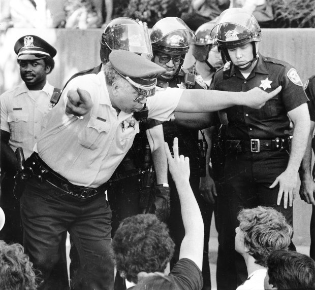 Evanston Police Cmdr. Donald Washington warns protesters to clear way from a bus carrying students arrested at an anti-apartheid demonstration and sit-in at the main administration building of Northwestern University in May, 1985. Ninety-five people were arrested during the five-hour demonstration. (Michael Fryer/Chicago Tribune)