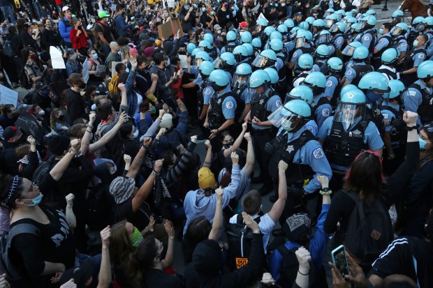 Police officers guarding the Trump International Hotel & Tower in Chicago hold back protesters on May 30, 2020, during a rally and march to remember the killing of George Floyd by a Minneapolis police officer. (John J. Kim/Chicago Tribune)