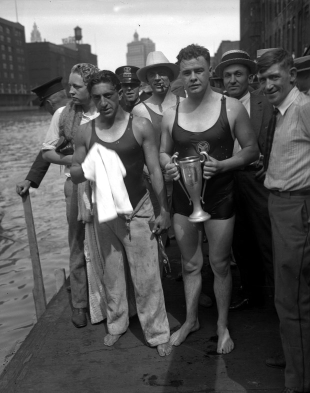 John Ball, of Peoria, second from left holding towel, who was with the Illinois Athletic Club, captured first place in the Chicago River swim race in July 1924. Paul Manovitz, holding trophy, of Northwestern University, came in second in a thrilling finish at the Chicago River swim. (Chicago Herald and Examiner)