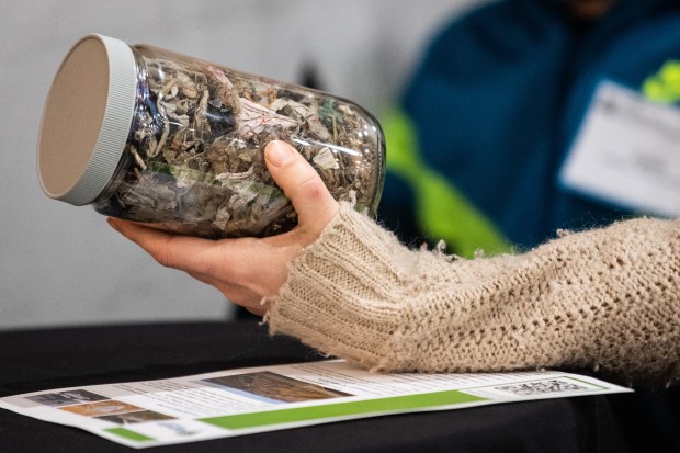 Gary Advocates for Responsible Development member Jennie Rudderham looks at a jar of "feed stock", used to make biofuel, during an open house to provide information about a proposed Fulcrum BioEnergy biofuels plant in Gary on Wednesday, Dec. 15, 2021. (Kyle Telechan for the Post-Tribune)