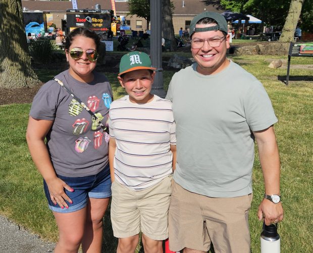From left, North Aurora residents Michelle Negro, her son Alex Jr. and husband Alex Negro enjoy a moment at the Cuisine at the Crossroads food truck festival Friday at Riverfront Park in North Aurora. (David Sharos / For The Beacon-News)