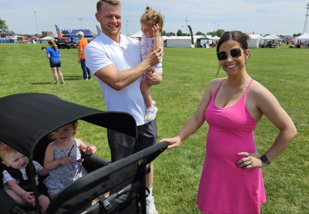 Chris Reed of Oswego holds his daughter Kaia, 1, while his wife Kristin holds on to a stroller Saturday at PrairieFest in Oswego. The festival runs through Sunday at PrairieFest Park. (David Sharos / For The Beacon-News)