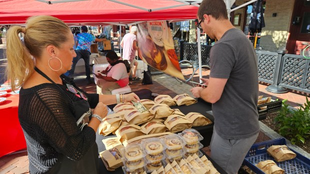 Beth Clark of Geneva makes a purchase at one of the vendors at the new Wednesday night version of the Batavia Farmers Market in Batavia last Wednesday. (David Sharos / For The Beacon-News)