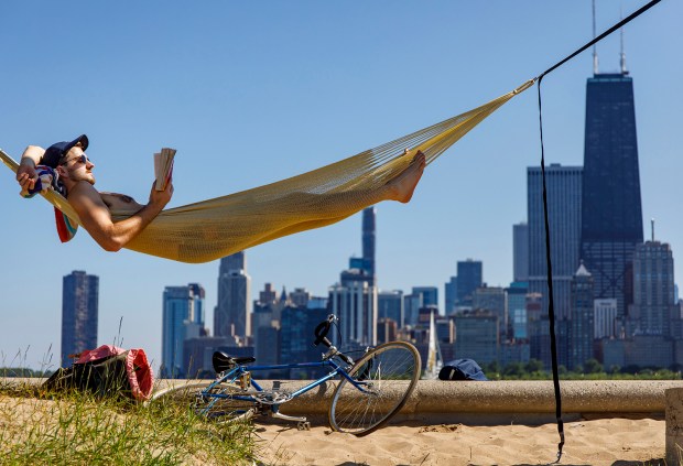 Ryan Keegan reads a book in a hammock along Lake Michigan at North Avenue Beach in Chicago, Ill. on Thursday, July 11, 2019.