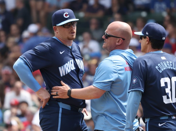 Cubs starting pitcher Jordan Wicks presses on his right lower back while talking with a team trainer in the second inning against the Cardinals at Wrigley Field on June 14, 2024, in Chicago. Wicks left the game after the meeting. (John J. Kim/Chicago Tribune)