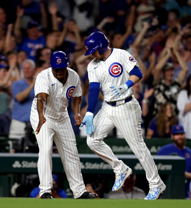 Chicago Cubs outfielder Ian Happ (8) celebrates with Chicago Cubs third base coach Willie Harris (33) after hitting a three-run homer in the bottom of the seventh inning during a game against the San Francisco Giants at Wrigley Field on June 17, 2024, in Chicago. Happ's homer put the Cubs ahead 6-3 but the lead did not hold. The Giants beat the Cubs 7-6. (Stacey Wescott/Chicago Tribune)