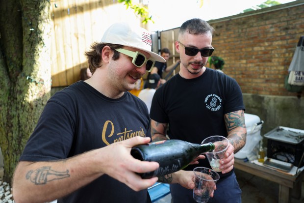 Sportsman's Club general manager DJ Dodd, left, pours Le Bouchon chef and owner Oliver Poilevey a glass of natural wine during a Sunday BBQ on the patio of Sportsman's Club in Ukrainian Village on June 2, 2024. (Eileen T. Meslar/Chicago Tribune)