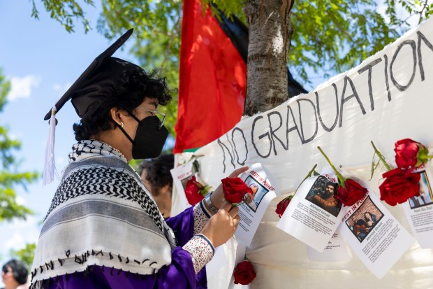 Graduates pin pictures and stories of Palestinian victims of the war in Gaza after several dozen of them walked out during Northwestern University's commencement on June 9, 2024, at the United Center. (Brian Cassella/Chicago Tribune)